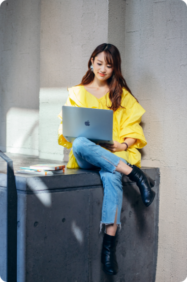woman in yellow sitting with a computer